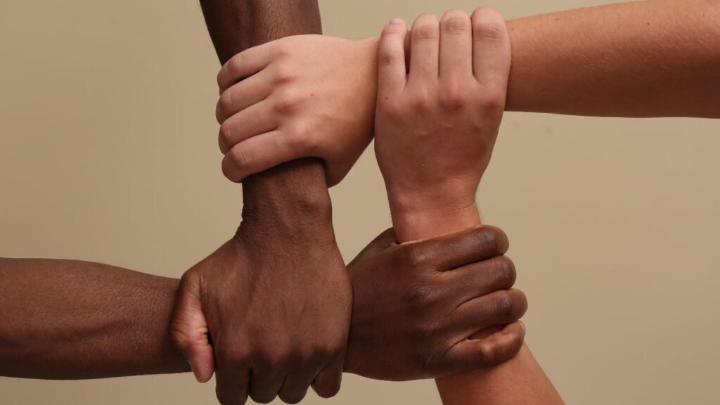 Men Joining Hands Together on Beige Background, Closeup