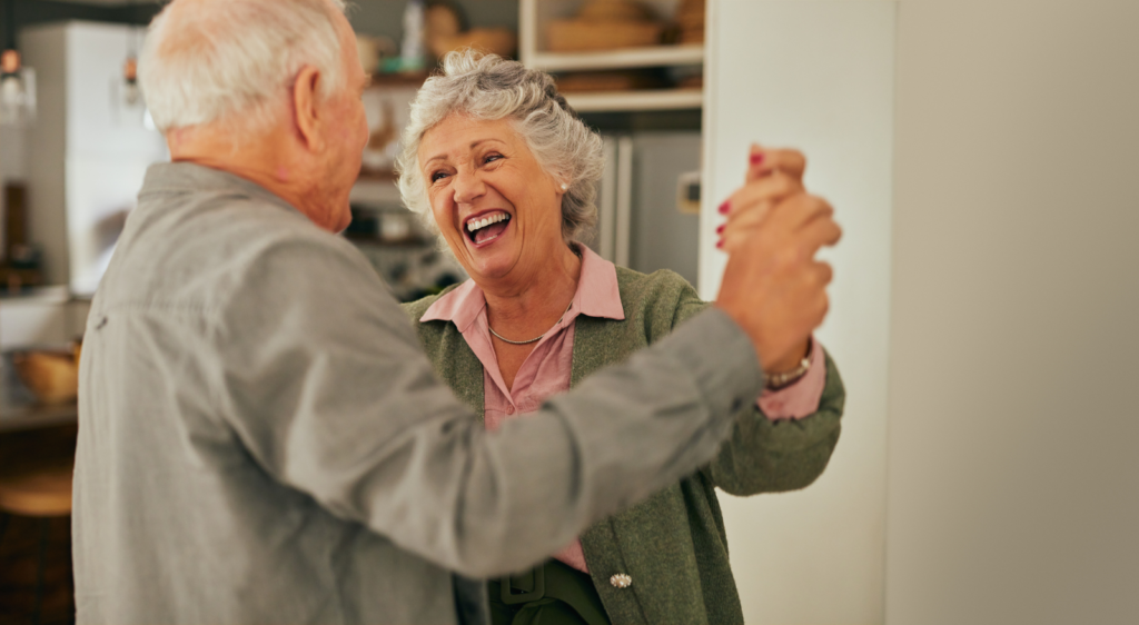 Old man dancing with joyful laughing woman at home