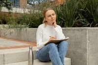 female sitting on steps reflecting with a book on her laps